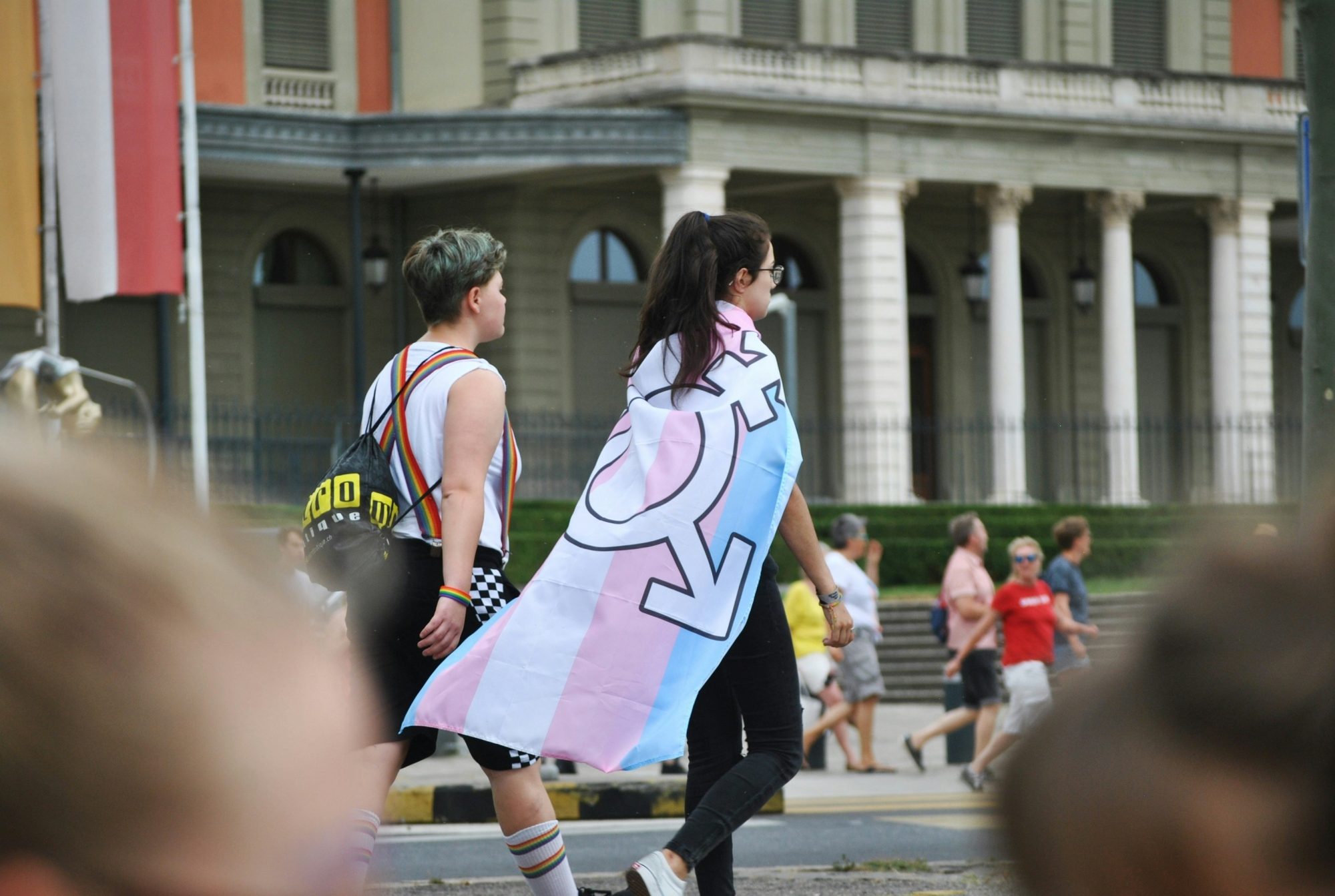 Deux personnes marchent avec un drapeau de la fierté trans