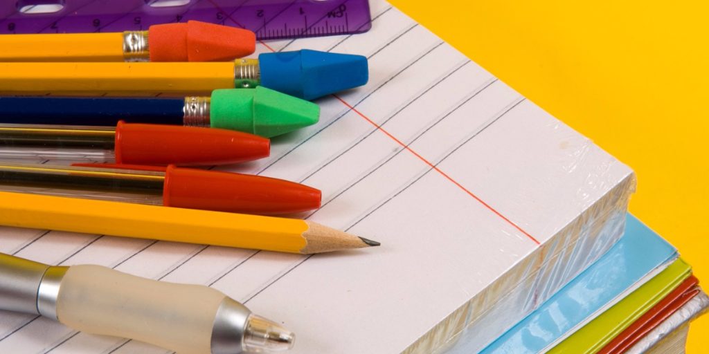 Des crayons et stylos sont posés sur un cahier