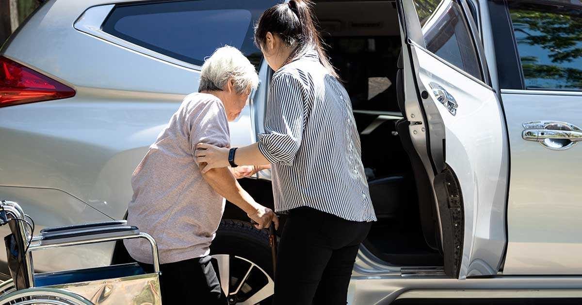 Une personne aide une personne en fauteuil roulant à monter dans une voiture