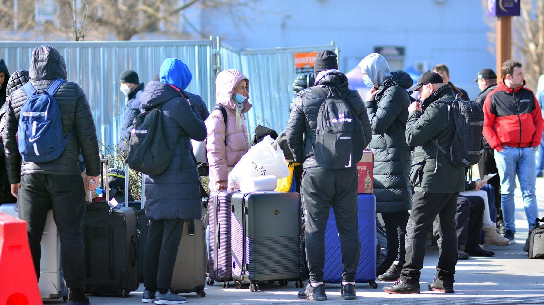 Des personnes font la file dans la rue avec leurs valises